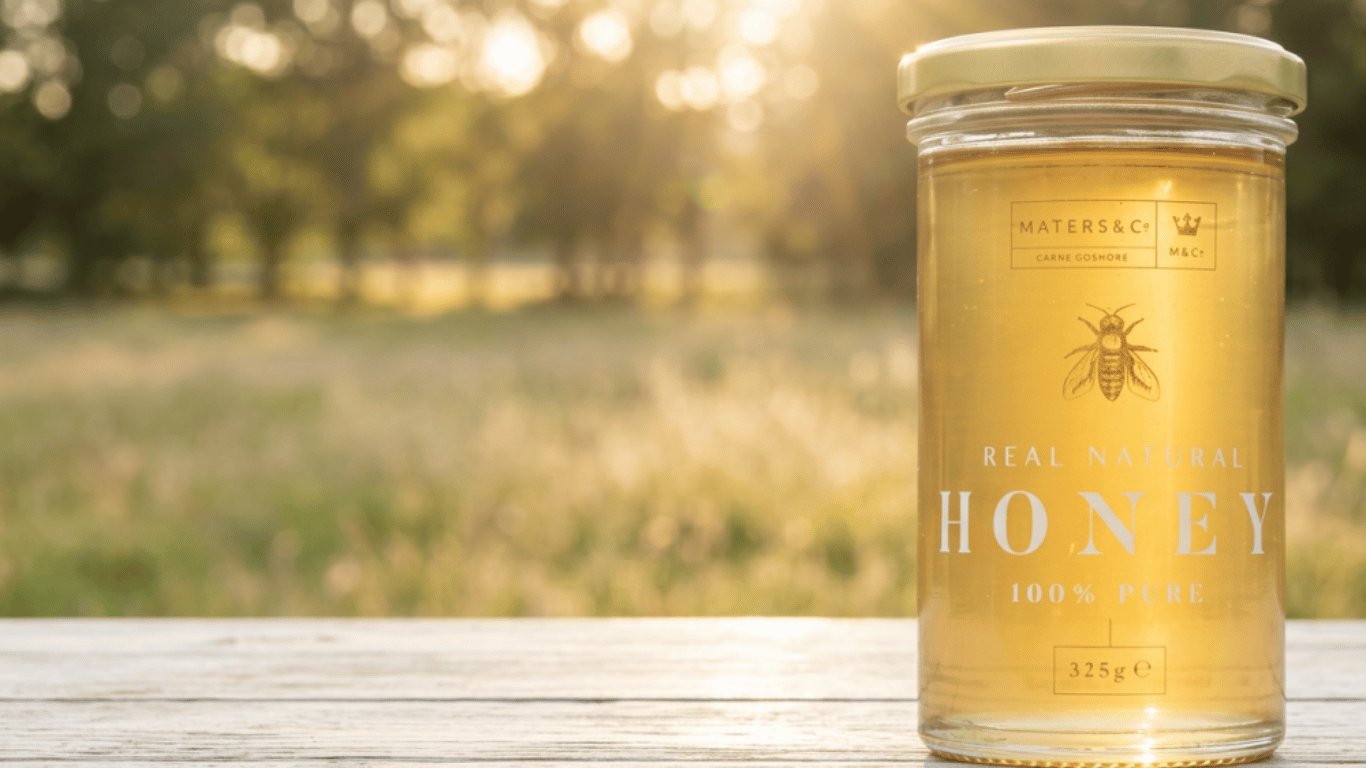 Jar of honey with a bee design on a wooden surface with a blurred natural background